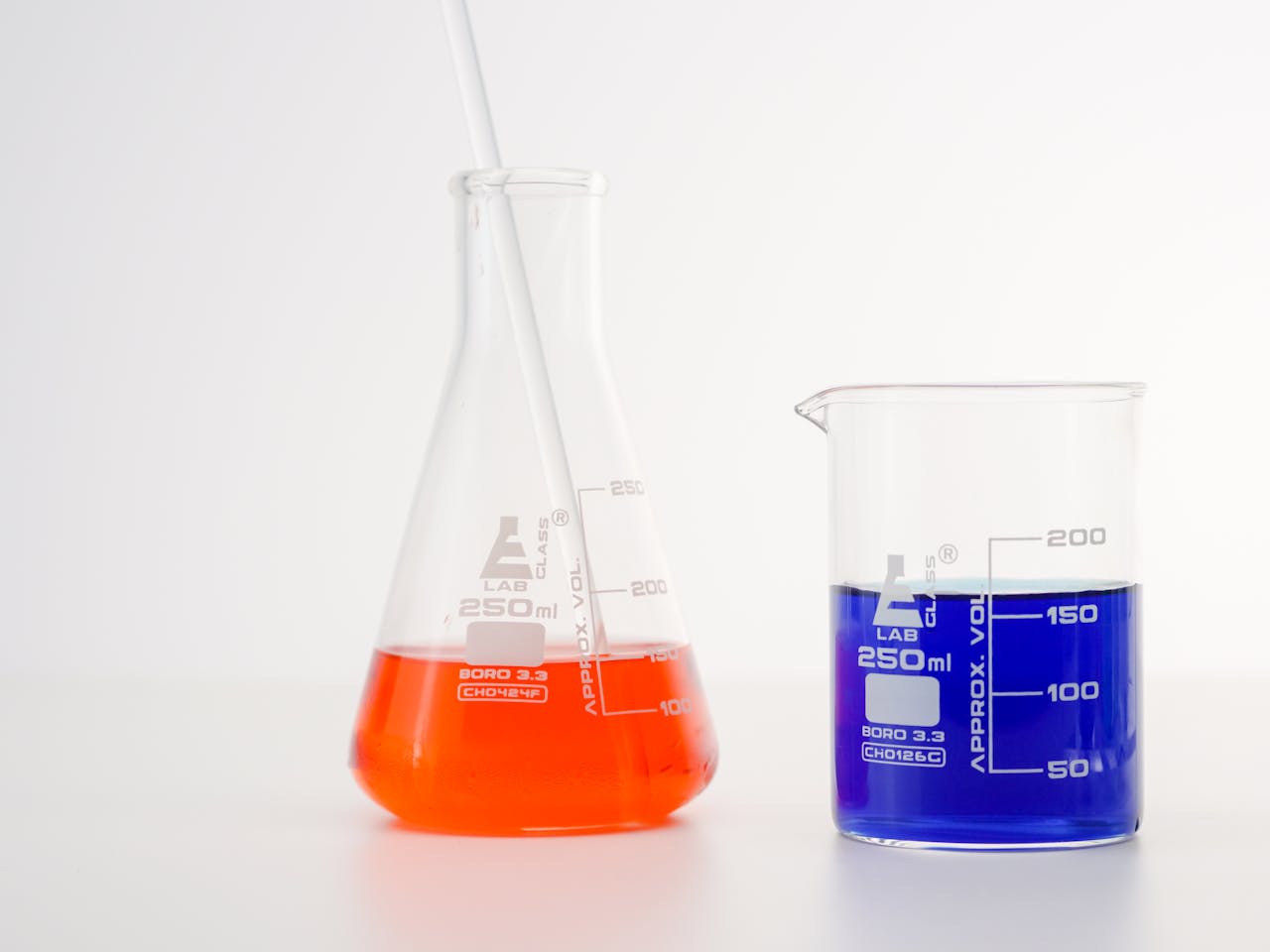 hero-img-01 Erlenmeyer flask and beaker with vibrant liquids for science research.